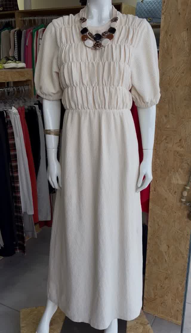 Vestido canelado off-white em manequim com colar dourado, na loja